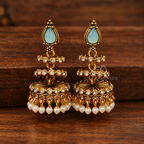 Gold-toned jhumka earrings with blue teardrop accents, clear stones and white bead fringes | SISTERHOODS-SHA256:bf6c73e31542396e90da25757fd50f908c41daea5dce73f88d5fc3e2da3a69cd