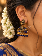 Ornate traditional jhumka earrings with divine motifs and blue bead accents | SISTERHOODS-SHA256:cd91184c7d2a296ae475ca50a5e458b327a4692689944ca4bc5a4caed3e7e901
