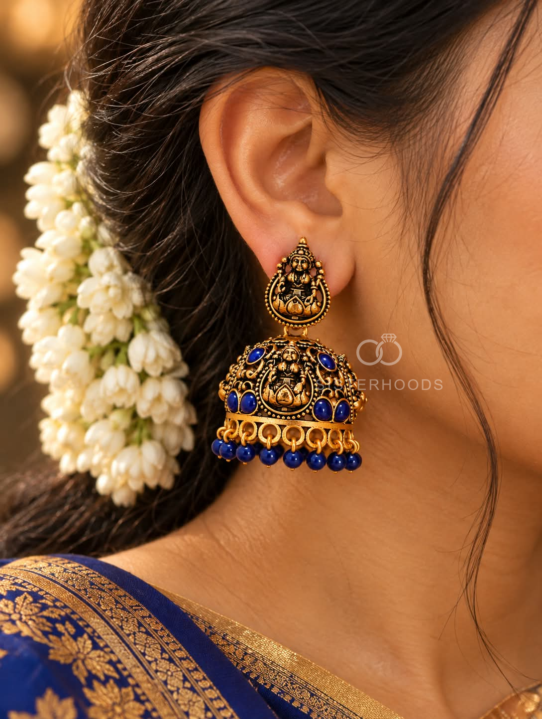 Ornate traditional jhumka earrings with divine motifs and blue bead accents | SISTERHOODS-SHA256:cd91184c7d2a296ae475ca50a5e458b327a4692689944ca4bc5a4caed3e7e901