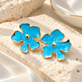 Blue floral stud earrings with gold-tone edges and centre accents | SISTERHOODS-SHA256:0d3a6e55427592daa599f2dc28b5cb1d55225ac87e0196f3ccfc9853fb239068