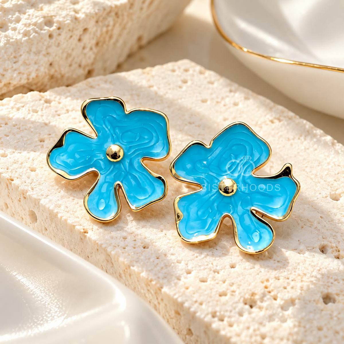 Blue floral stud earrings with gold-tone edges and centre accents | SISTERHOODS-SHA256:0d3a6e55427592daa599f2dc28b5cb1d55225ac87e0196f3ccfc9853fb239068