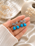 Blue drop earrings with textured bow-shaped accents | SISTERHOODS-SHA256:dc87ed944737078e8e2d0f520f6b8b1cbd7c9cc657b77cb794401cc30bffea50
