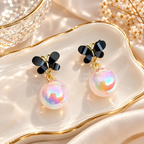 Black floral stud earrings with iridescent pink pearl-style drops | SISTERHOODS-SHA256:b11c4b5374528a5bd522690b94e3f734f589bacd9547a07f39e7c8add3ff1823