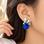 Blue faceted dangle earring with white flower, pearl accent and butterfly charm | SISTERHOODS-SHA256:e3640d45c000a21b786e4d8386f82727e1924ad1b50b7f35678d4ef9c08a46e6