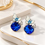 Blue faceted dangle earring with white flower, pearl accent and butterfly charm | SISTERHOODS-SHA256:66f37bbb877a8639564865b1c5c592cc49261b3cffcc44ff1607517c8a09a27e