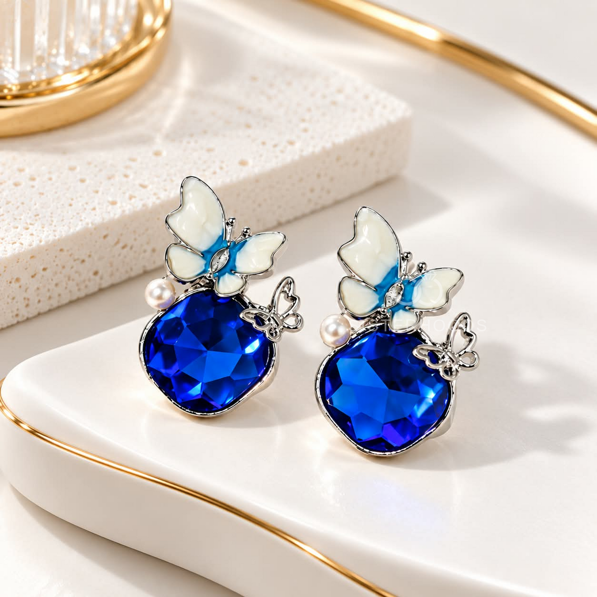 Blue faceted dangle earring with white flower, pearl accent and butterfly charm | SISTERHOODS-SHA256:66f37bbb877a8639564865b1c5c592cc49261b3cffcc44ff1607517c8a09a27e