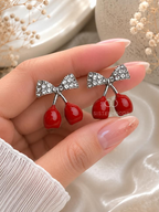 Silver bow drop earrings with red cherry-shaped dangling charms | SISTERHOODS-SHA256:c273bb88c7add084f9de1b219e3d290cd63189dfd2f0e42742ad01bcea0690e1