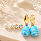 Three pairs of earrings featuring white bead studs, clear accent studs and blue drop earrings with gold-tone leaf tops. | SISTERHOODS-SHA256:692839472970e3db41300df234436f1bd5f31dbf95eb5b54f6b2aa7fe87edf27