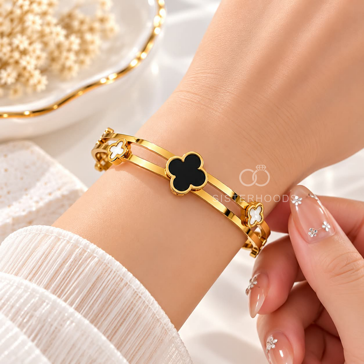Gold-tone cuff bracelet with black and white clover accents | SISTERHOODS-SHA256:b5b0bbb15e8da01d22084090fa6755acfb82ad79b3347dd65de52b507f4d59f2