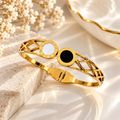 Gold-tone cuff bracelet with black and white circular accents and geometric openwork | SISTERHOODS-SHA256:357f7eb1d3b522223c1f989850faae6c1c8d100675488b9d72e646313bcc4eec