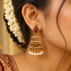 Gold-tone traditional jhumka earring with red teardrop accent, crystal details and white pearl fringe | SISTERHOODS-SHA256:83f32d45743b7217d51915d374ddd29fa2e3062acfe5fad3c96580cd867fcaf4