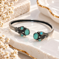 Silver and black open cuff bracelet with turquoise oval accents and ornate detailing | SISTERHOODS-SHA256:7a51ec8eccf77526e450cbe6d5cdb81f8ccc57b3df7c97b5056b6ae21d58f0fc