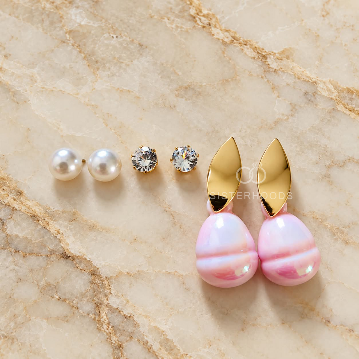 Three pairs of gold, pink and white earrings including pearl studs, sparkling studs and pink drop earrings. | SISTERHOODS-SHA256:1b96bd89fc157b5a6fd98935a965f8c3998f7de6de1a7c504ce178c9e8921b31