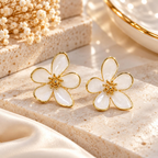 White five-petal floral stud earrings with golden outlines and textured centres | SISTERHOODS-SHA256:04f52583fcf3fd44c4fda57b204f97a9ca396b2e42ec548253a281fbbf75d0e5