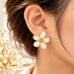 White five-petal floral stud earrings with golden outlines and textured centres | SISTERHOODS-SHA256:4ec1a5e222b65270a8aaa3390a9f44bb526411c3151810429fc712901cdd28cd