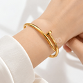 Gold open cuff bracelet with a sleek bar detail worn on the wrist | SISTERHOODS-SHA256:9ef14449ddc8f5c51334dbbff1d9656cf26ef7c089d9efefa7dd8b17f4ac8eb7