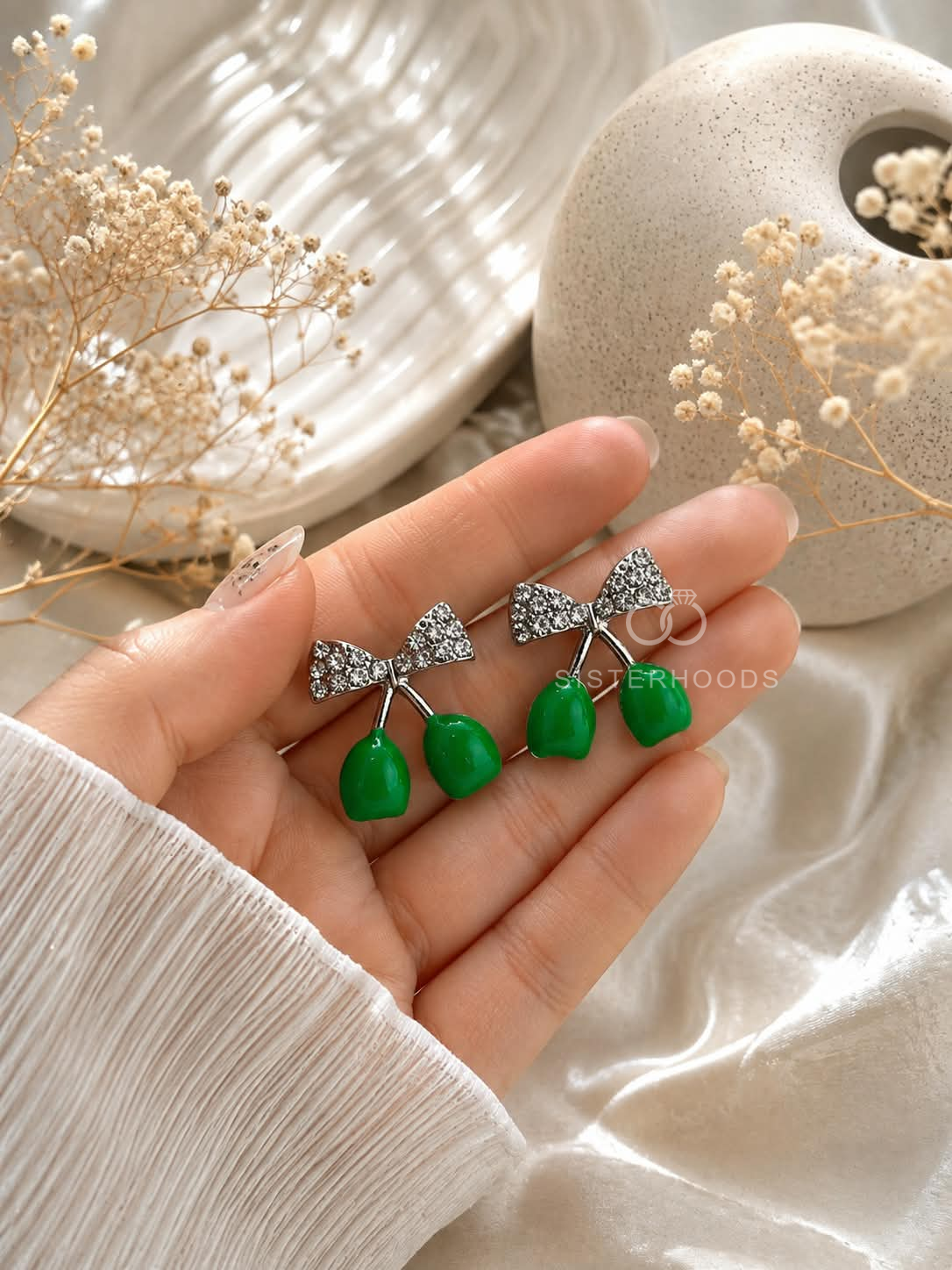 Silver bow-shaped dangle earrings with glossy green drop accents | SISTERHOODS-SHA256:e199773fa9dc2155dca640fac7aaa77acbf72a05421dc78a57538d4b8fdc0307