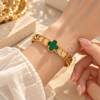 Gold-tone open bracelet featuring a green clover centre and floral cutout details | SISTERHOODS-SHA256:c10db9d1445762b24b616643595b583a889d91f4b2a46d96669c30ed60ecccc6