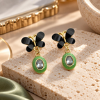 Black floral top dangle earrings with green oval accents and clear faceted centres | SISTERHOODS-SHA256:106568098da66f685c09c0d234bd2885c9595a0533bcbbfa186f0796659b01c3