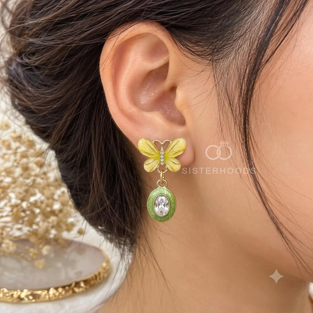 White butterfly earrings with green oval dangling accents and clear centre details | SISTERHOODS-SHA256:93ba8783c9de5f0bff3ce14ad9be6cea6213abac2894b4395ca188b6800467e1