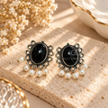 Black oval dangle earrings with ornate silver-toned detailing and white bead drops | SISTERHOODS-SHA256:47880efdec1b6c756ad0cfe4ca32e53c531be67a5eb3d3d7171e6fa781b677a2