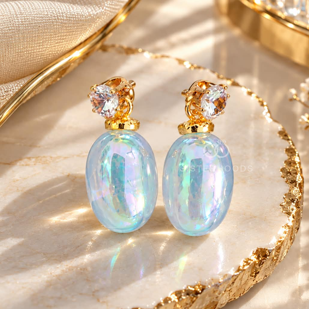 Gold dangle earrings with iridescent blue oval drops and faceted clear accents | SISTERHOODS-SHA256:7243dd086c51c1cec9d1fef016089704ee88f1bd5a499917630ea8205db384fa