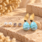 Gold-tone leaf stud earrings with luminous aqua-blue rounded drops | SISTERHOODS-SHA256:d4492a4c8d4aa59696943c7e9986e7f000c7c3e0a1d05a417b15bd97159ea5dd