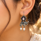 Oxidized elephant and lotus dangle earrings with black, pink and pearl-like accents | SISTERHOODS-SHA256:8b748047746a636f353ec0c3c3616bf1c19a9976d479ddab7204f668793f401a