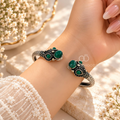 Ornate adjustable cuff bracelet with green accents and detailed dark patterns | SISTERHOODS-SHA256:040bc90ecbf6f096c8a7b464bb1f7dcab95f1477e623cb8a2bb362b812fbdcc4