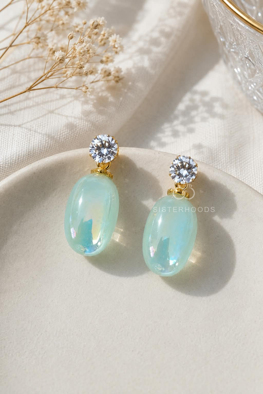 Pale aqua oval drop earrings with clear faceted round accents and gold-tone details | SISTERHOODS-SHA256:f0ce97b162340be04f92117ca9bb1bd14ae1ecb974cc59b5a32165ef1df503a1