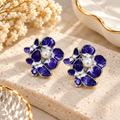 Purple floral stud earrings with white pearl-like centre accents and silver-toned edging | SISTERHOODS-SHA256:e9ca995f2be6b29f786e00593ed1cf7be18c3cd6e039ca7eeb1b44ab918ec7f4