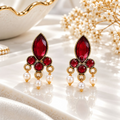 Gold-tone dangle earrings with red faceted accents and white bead drops | SISTERHOODS-SHA256:3827b394eadf31b5e14a0842ffc2dae239af2642b9c8bcd85efa4b2a6e17f0a9