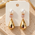Gold drop earrings with white pearl tops, square crystal accents and polished teardrop pendants | SISTERHOODS-SHA256:63476b54c936a55371f249efc70e15fad52bd135bc55ad4bcb0865bf501816bd