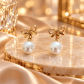 Gold-tone knot stud earring with a white pearl drop | SISTERHOODS-SHA256:b348bed07b74dc5e0e39a461890a245f3f268e108e564d54bbcc7b4bb529c954