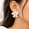 White blossom-shaped gold-tone stud earring worn on an ear | SISTERHOODS-SHA256:4871f247b650aa4756377d8c538ef307b06d741202757feeab30bd9a89465fc5