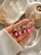 Silver-coloured bow dangle earrings with bright pink drops | SISTERHOODS-SHA256:be9a66a40dd8ffa813c91cd4ffdd881db604db0ef2110820278a248697fe19e6