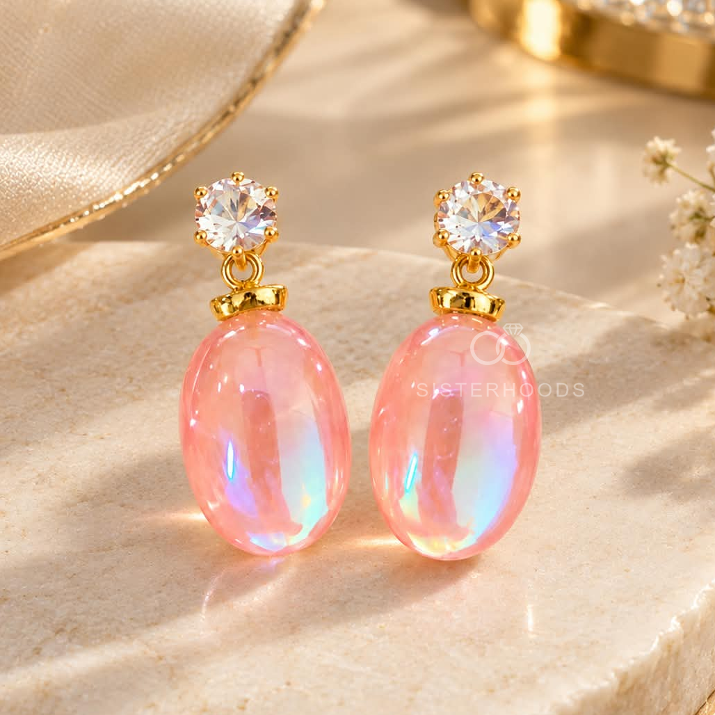 Pink iridescent oval drop earrings with clear faceted studs and gold-tone accents | SISTERHOODS-SHA256:0132d08cc032a74bd378b21b2cfbee832d399ad6b109e7aa89bc2340d5bb7abd