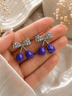 Silver bow earrings with glossy purple cherry-shaped drops | SISTERHOODS-SHA256:0bb335c5031fc0fd9274823e5cacd85b54f85d04597876a50993aee63c6cbd4d