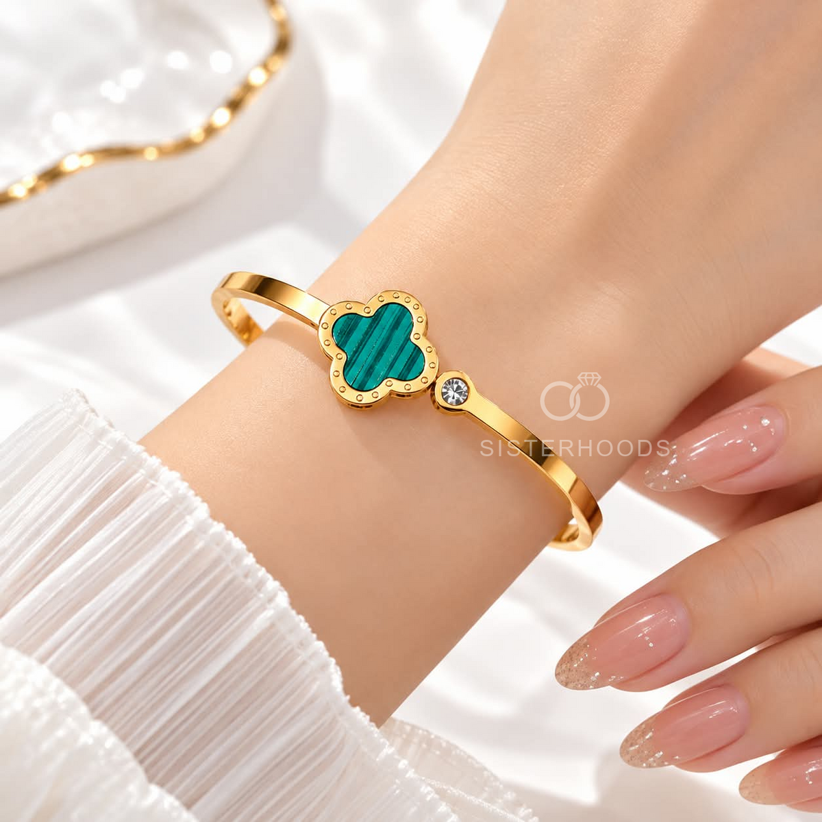 Gold-tone cuff bracelet with a teal quatrefoil centre and small accent detail | SISTERHOODS-SHA256:0798b5ac9fad391b8fcec2b87c67e6cbdcebfd98c89cdc15f9ee73e987caf01e