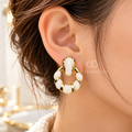 Gold-tone Korean dangle earrings with circular white accents on a model's ear. | SISTERHOODS-SHA256:cc8b8985d67d9955d6f81bbb41bd96f3fff865e3d8df4199a8aeac0e00962327