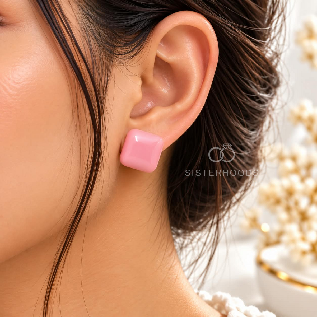 Pink square stud earring worn on an ear | SISTERHOODS-SHA256:0af19de3abf42d02af4d2f16389975ad362668f81295cedc917b0a00aeddc8f5