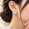 Round mint green iridescent stud earring worn on an ear | SISTERHOODS-SHA256:be891b58f4281f5ad8b5f436ea4dce393e61b4d1617ac8047281008077b65f05
