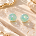 Round mint green iridescent stud earring worn on an ear | SISTERHOODS-SHA256:459377c45f41596d68cd2cb82b949b1eca2c47ff67f1636f0a5ac1664c2069d7