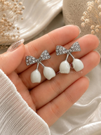 Silver bow earrings with white dangling drops | SISTERHOODS-SHA256:06ac72d69c90b948bb53ab9c8a93fe00d972d67b4df9ad20b718b19af8cc5b97
