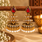 Gold-tone jhumka earrings with red teardrop accents, clear stones and white pearl drops | SISTERHOODS-SHA256:9696a1f11d06a8ca7dbff50c5c629adaba691242bb02712bff6c8e7b53a757b9