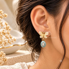 White floral drop earrings with turquoise oval accents and clear centre details | SISTERHOODS-SHA256:73ea84df2082c82c474cdb22b59e1f20faab56346f0f896019fe3e0e59514fc2