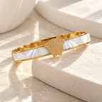 Gold-tone open cuff bracelet with white central band and portrait motif | SISTERHOODS-SHA256:1c591a451461993bb31f868bb2ba2426ae9c500561e1a077394adec6b1001060