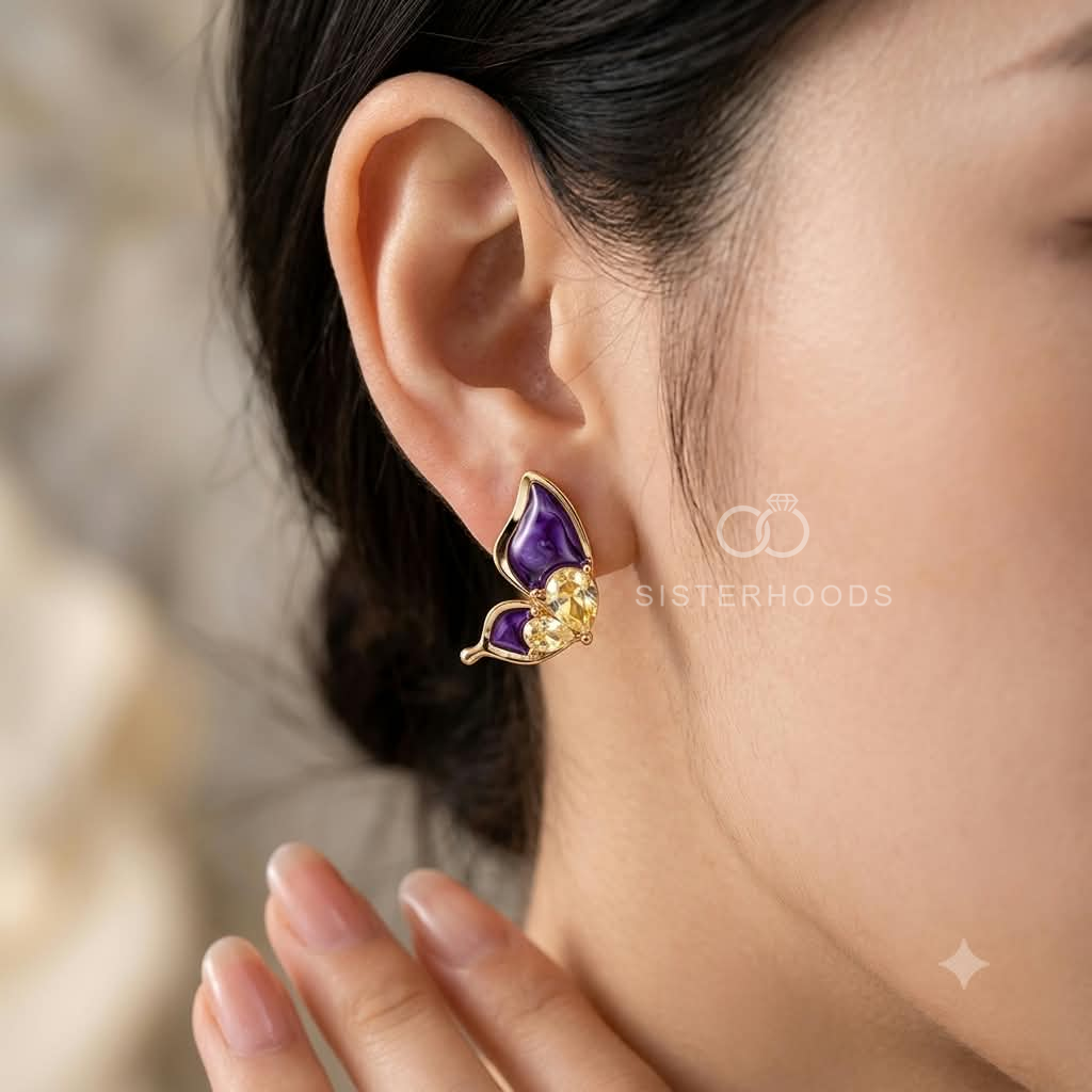 Purple wing-shaped stud earrings with faceted accents and gold-tone detailing | SISTERHOODS-SHA256:8ebf5463d5f9566c414181f458f5e45b80cb3eed8a20ed473d2ea636da4e2b8e